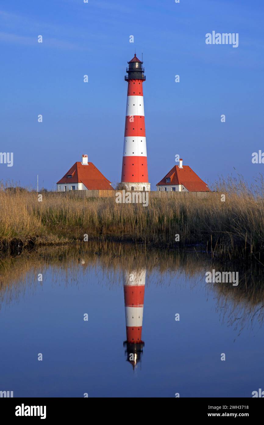 Faro di Westerheversand riflesso nello stagno di Westerhever al crepuscolo, penisola di Eiderstedt, parco nazionale del mare di Wadden, Frisia settentrionale, Germania Foto Stock