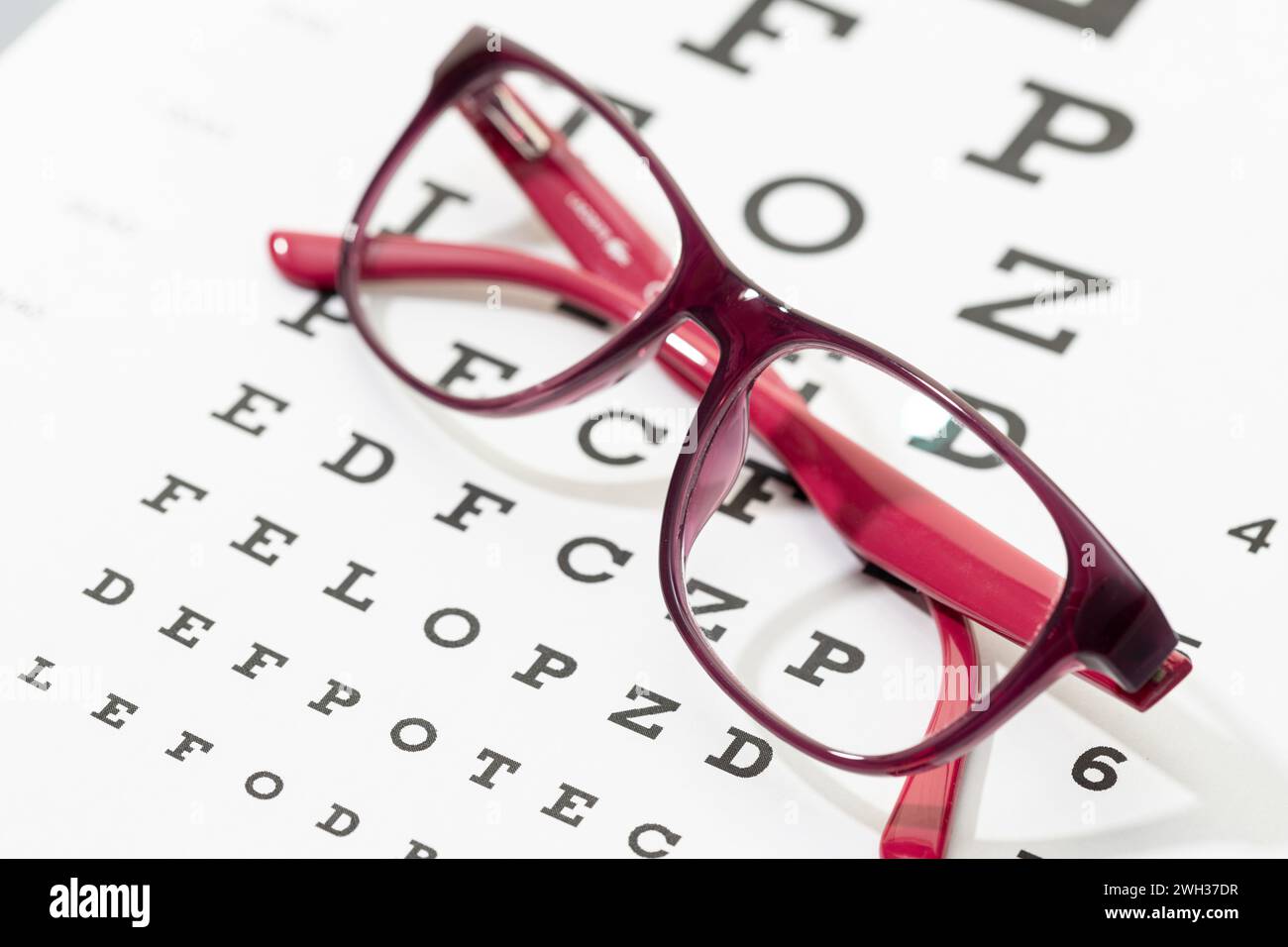 Occhiali femminili sulla tabella dei test di visione. Oftalmologia, vista, concetto ottico Foto Stock