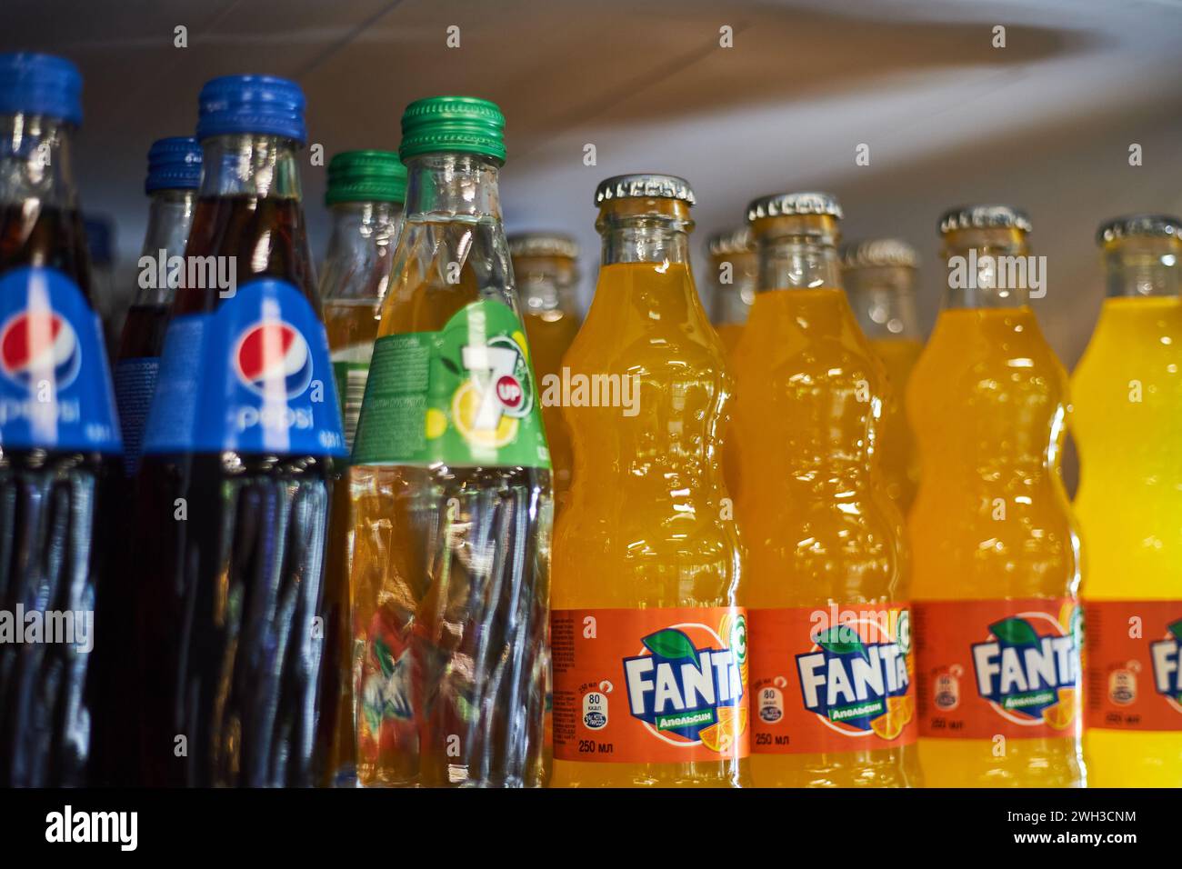 Pepsi, 7 in su, Fanta. Bottiglie di bibita in vetro di marca concorrente su un ripiano del frigorifero presso il supermercato. Bevande, bevande analcoliche gassate più diffuse Foto Stock