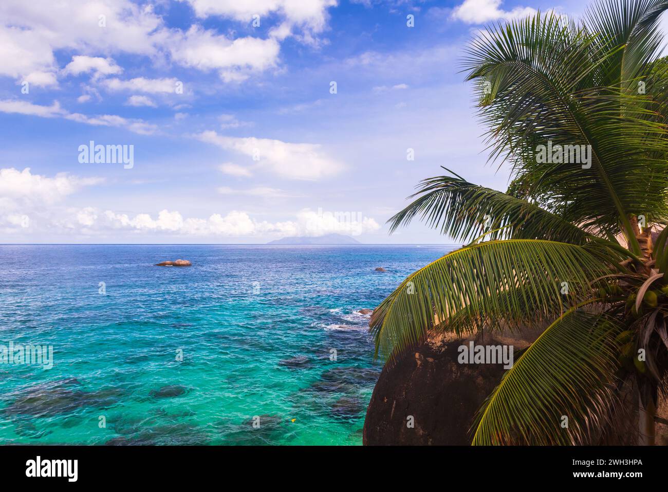 Vista costiera della spiaggia Vista do Mar dell'isola di Mahe, delle Seychelles, delle palme e dell'acqua blu dell'oceano sotto il cielo nuvoloso in un giorno d'estate Foto Stock