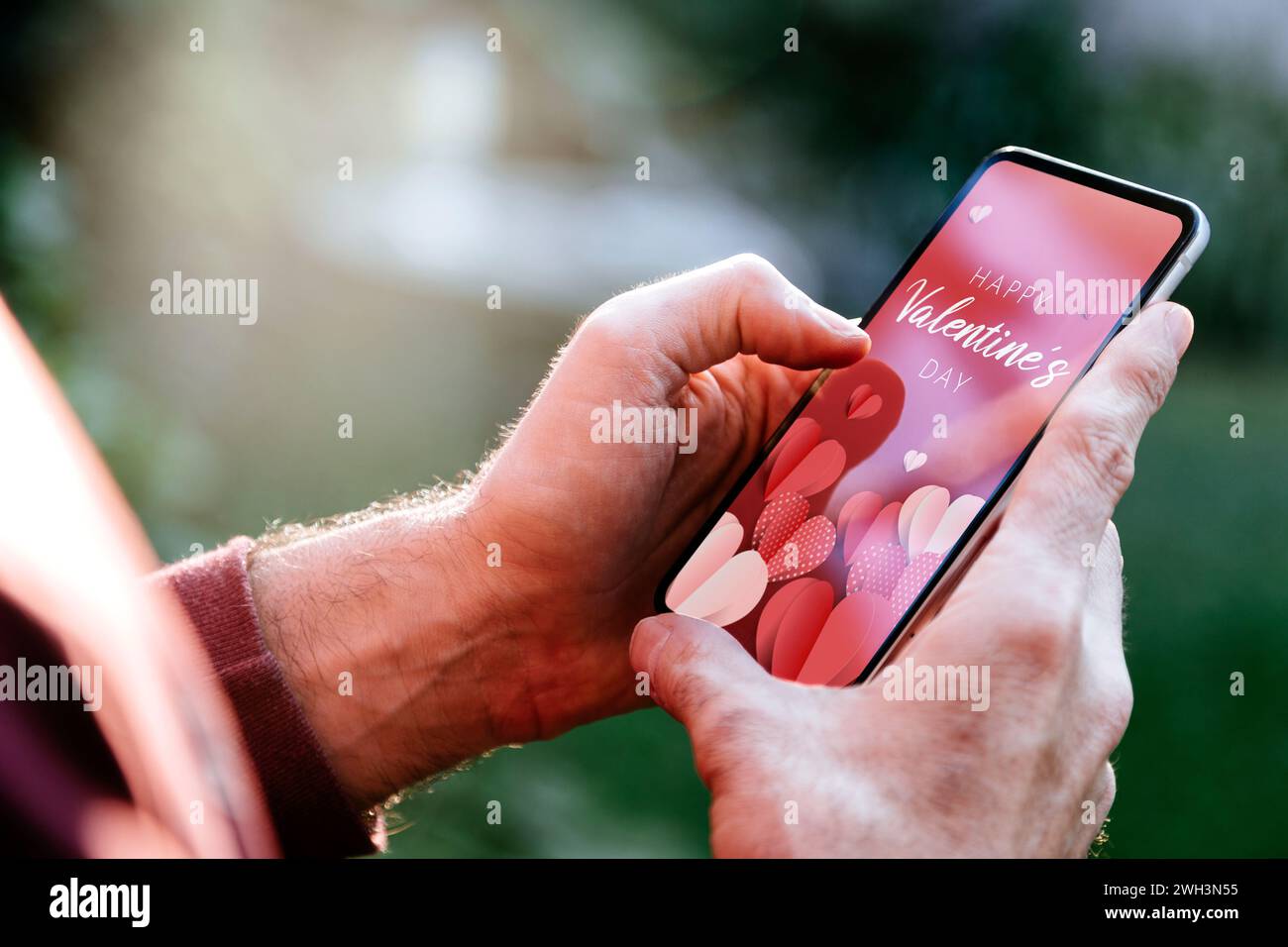 Uomo che mostra un biglietto d'auguri digitale di San Valentino sullo schermo del telefono cellulare. Foto Stock