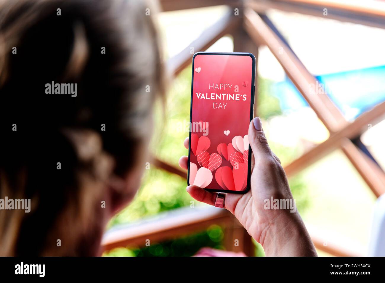 Donna che mostra un biglietto d'auguri digitale di San Valentino sullo schermo del telefono cellulare. Foto Stock