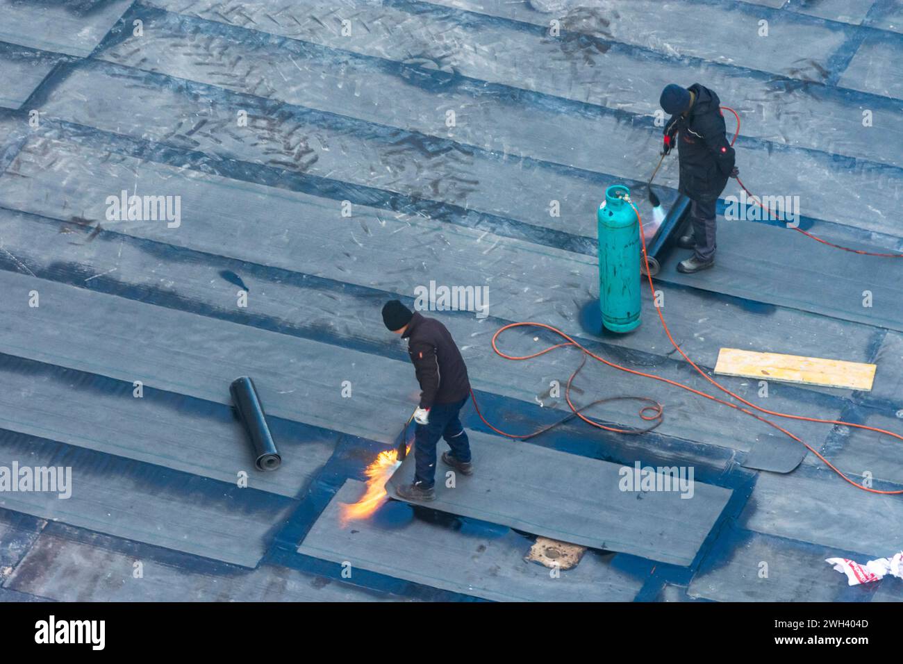 Operai edili che svolgono lavori di impermeabilizzazione su un soffitto di un edificio con membrane bituminose Vienna 22. Donaustadt Wien Austria Foto Stock