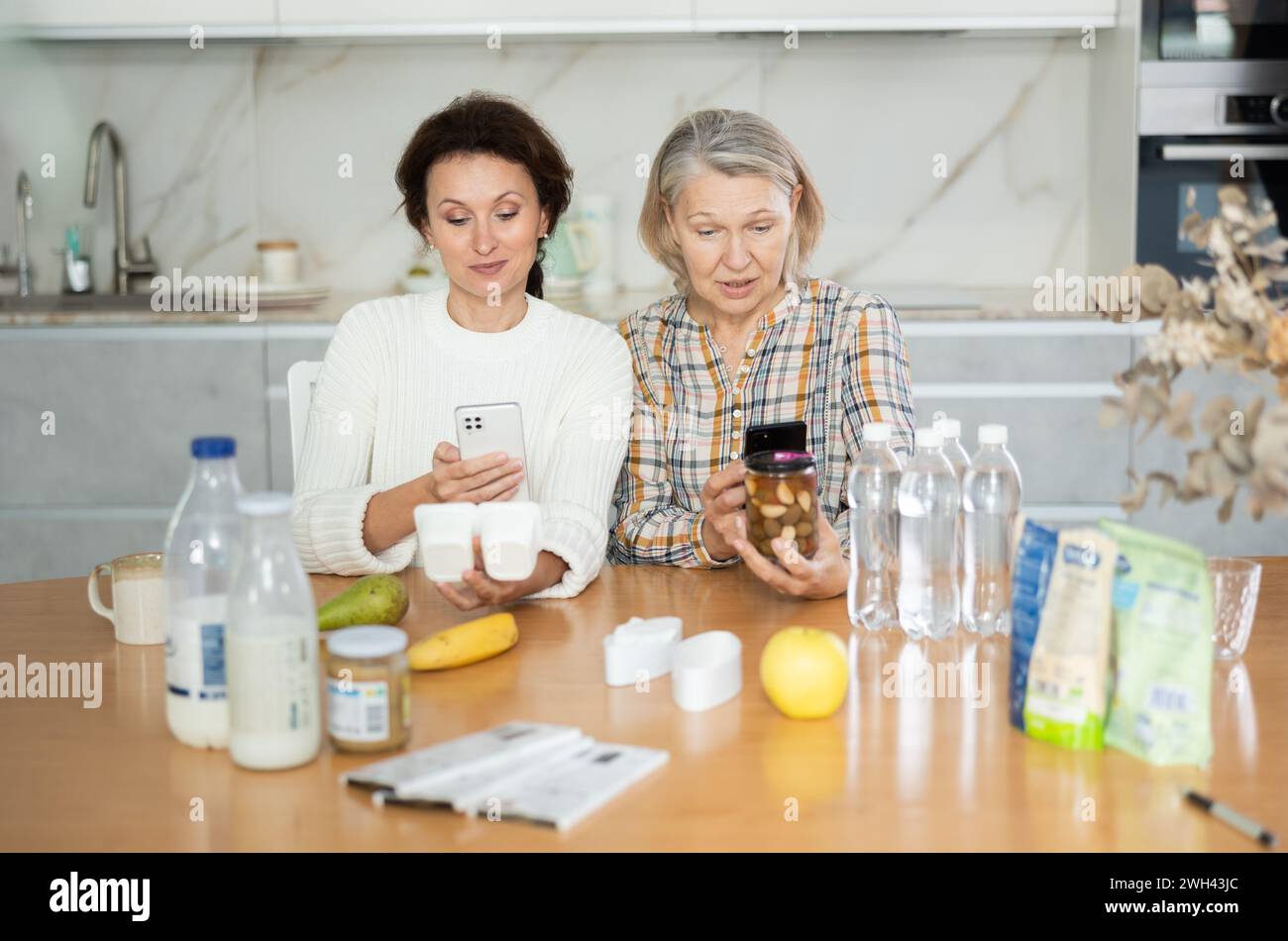 Due donne che scansionano prodotti diversi utilizzando il proprio smartphone Foto Stock