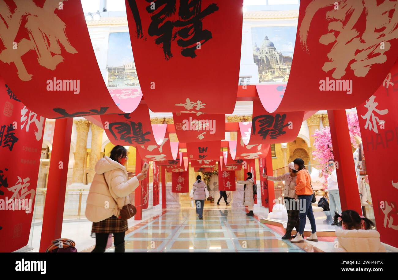 SHANGHAI, CINA - 7 FEBBRAIO 2024 - i turisti fanno acquisti al Moon Star Global Harbor Mall, decorato con un tradizionale "totem del drago" cinese Foto Stock