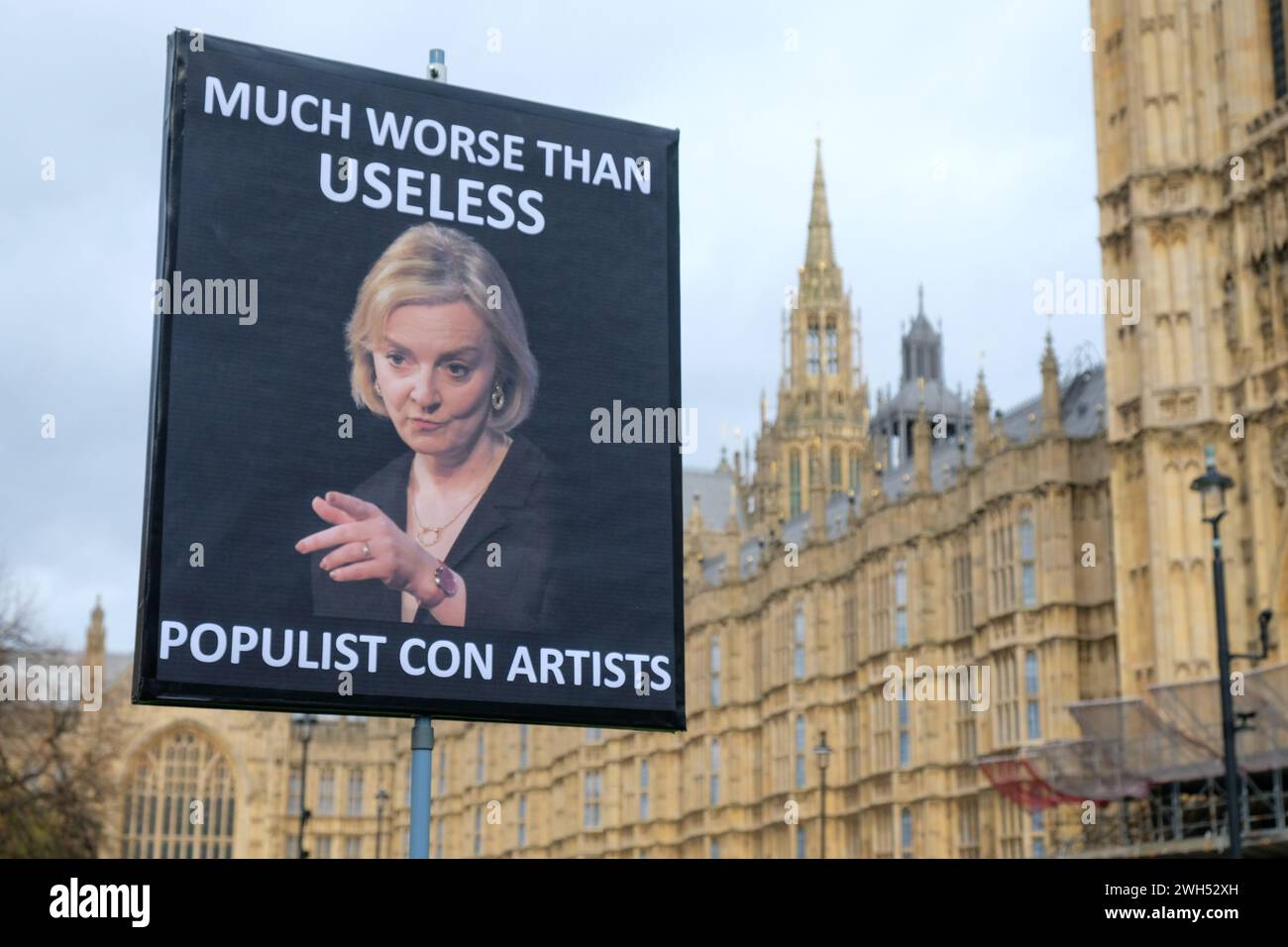 Londra, Regno Unito. Un cartello attivista sullo sfondo del Parlamento recita: "Molto peggio che inutile. Popolari truffatori. Foto Stock