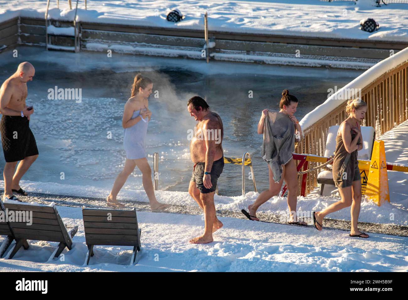 Le persone che entrano e escono dalla sauna nella piscina coperta di neve Allas Sea Pool di Helsinki, Finlandia Foto Stock