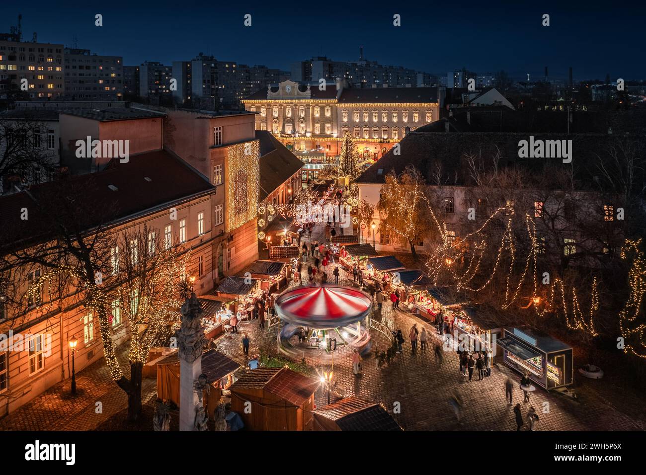 Budapest, Ungheria - Vista aerea del mercato di Natale e della giostra in Piazza Szentlek, Obuda al tramonto. Negozi decorativi illuminati, decorazioni natalizie Foto Stock