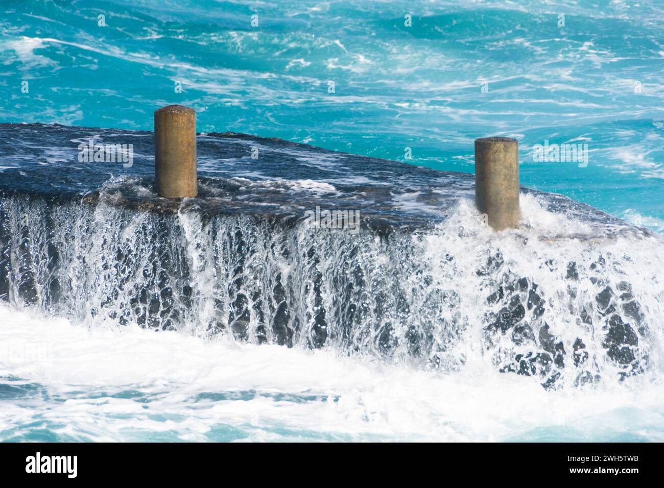 Le onde oceaniche si schiantano contro i getti, creando uno splendido spruzzo d'acqua marina. Foto Stock