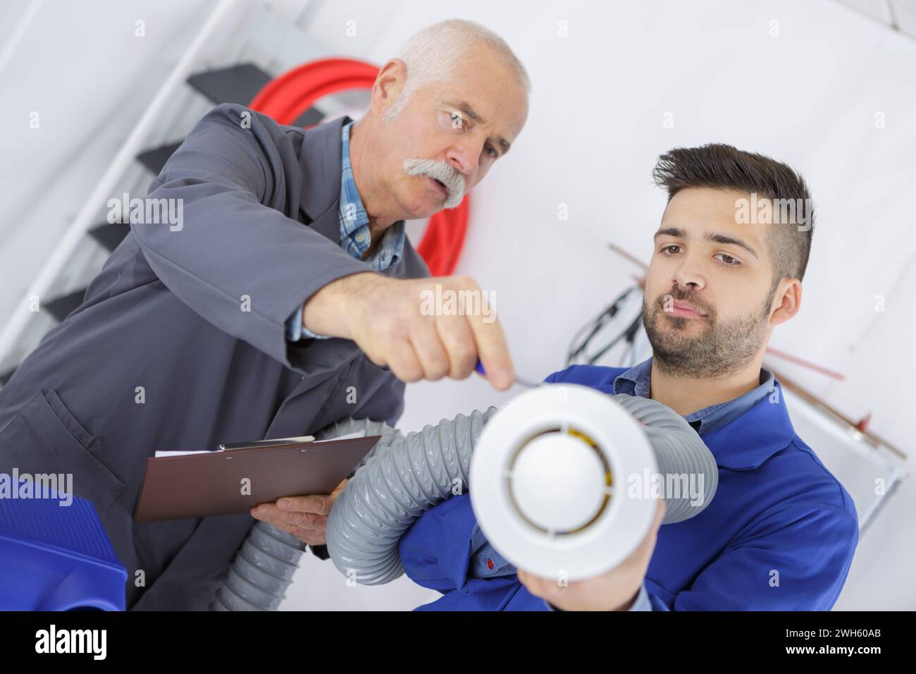 Uomini che detengono parti del sistema di ventilazione Foto Stock