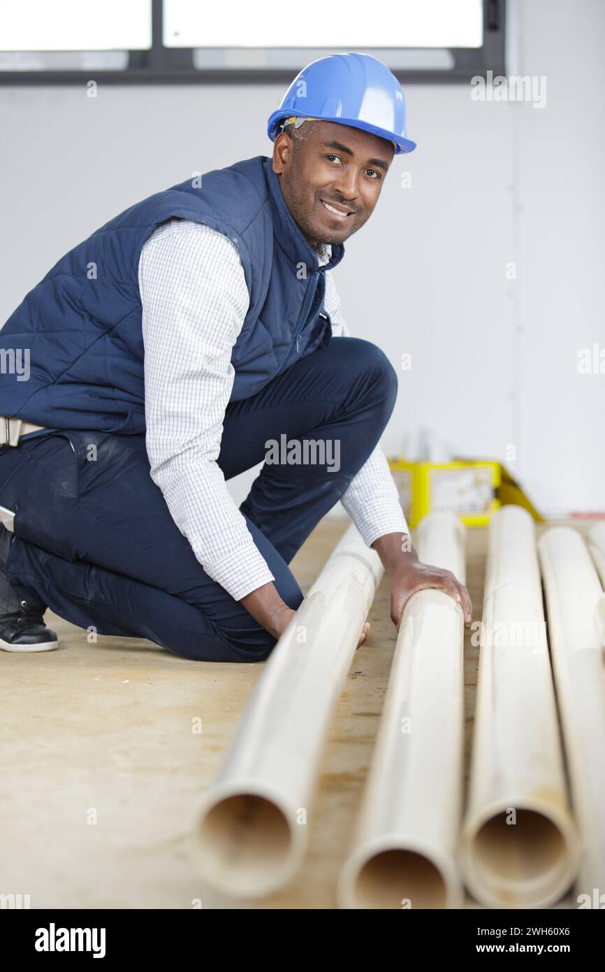 uomo inginocchiato con utensili idraulici Foto Stock