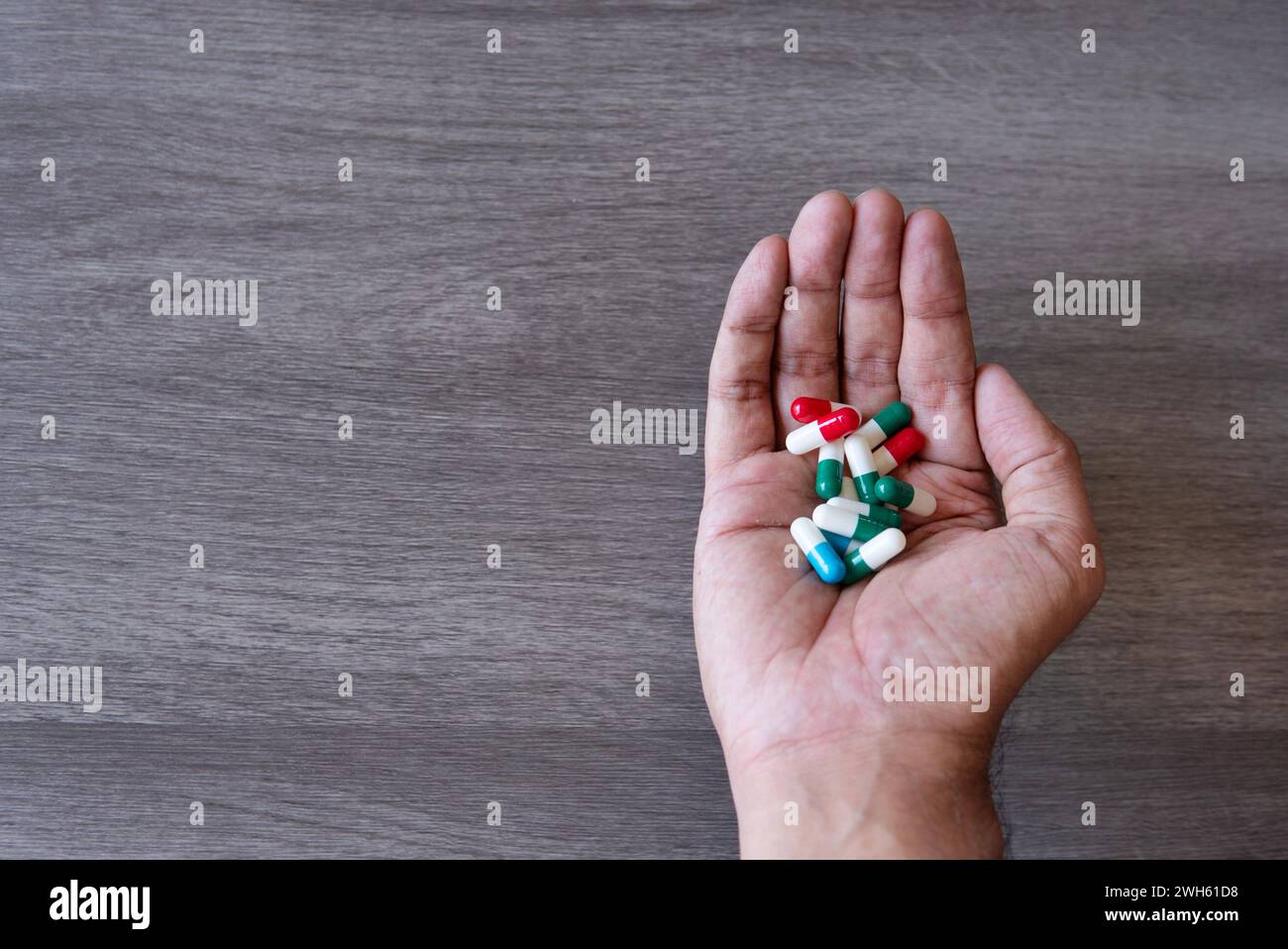 Mano che tiene una pila di pillole colorate. Copia spazio per il testo. Abuso di droga, concetto di dipendenza. Foto Stock