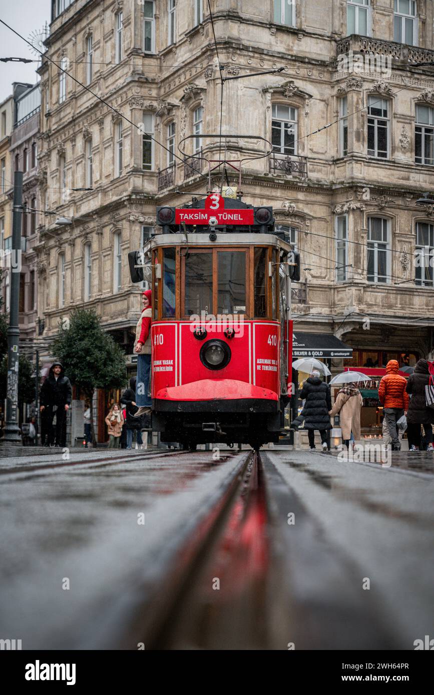 Rainy Rendezvous: Il tram rosso delle strade bagnate di Istanbul Foto Stock