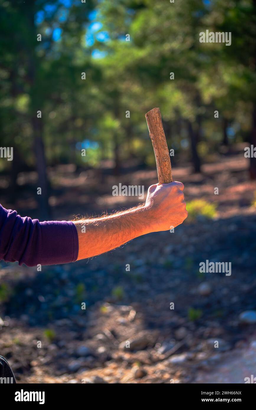 Un uomo determinato che mette in mostra la sua abilità artigianale, tenendo in mano una robusta asta di legno, una testimonianza dell'arte e della dedizione del lavoro artigianale Foto Stock