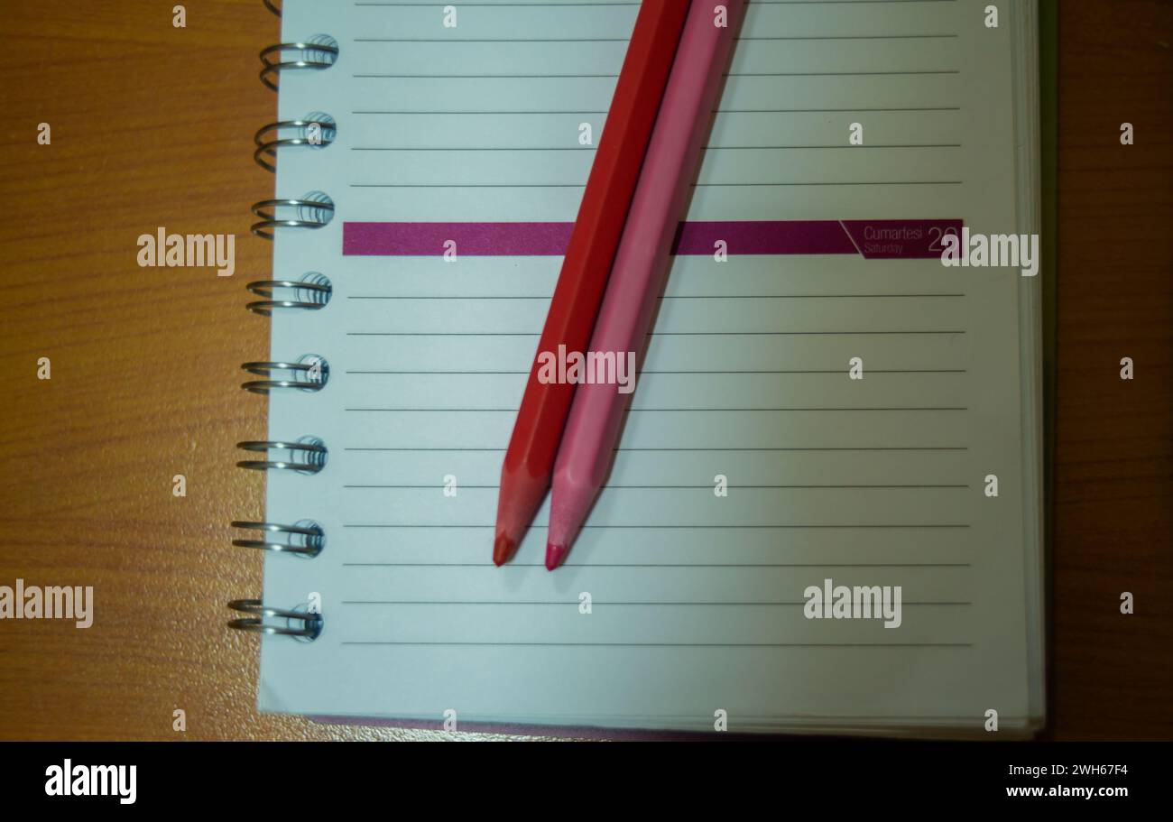 Un vivace paio di matite rosa si appoggia su un notebook, offrendo strumenti artistici e colorati per l'espressione creativa e l'apprendimento in ufficio o a scuola. Foto Stock Un vivace paio di matite rosa si appoggia su un notebook, offrendo strumenti artistici e colorati per l'espressione creativa e l'apprendimento in ufficio o a scuola. Foto Stock