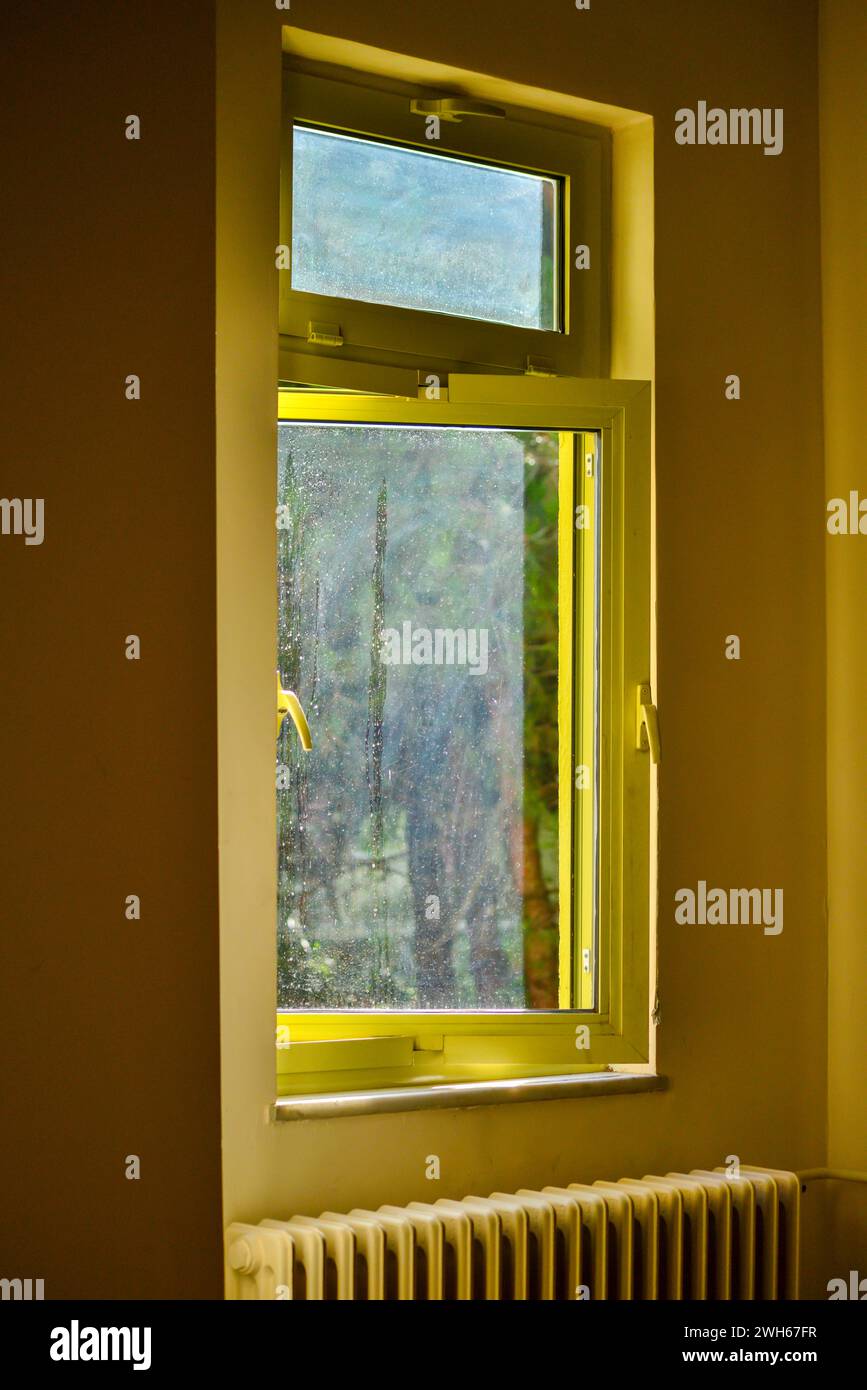 Una vista calda e intima attraverso la finestra gialla interna, dove la luce del sole inonda la camera di un vibrante bagliore. Foto Stock
