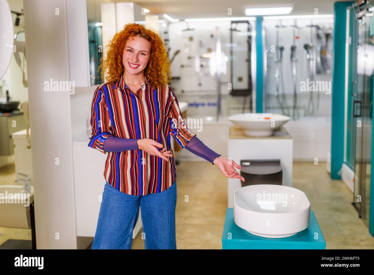 Ritratto del venditore nel negozio di articoli da bagno. Una donna rossa felice lavora nel negozio di bagni. Occupazione delle vendite. Foto Stock