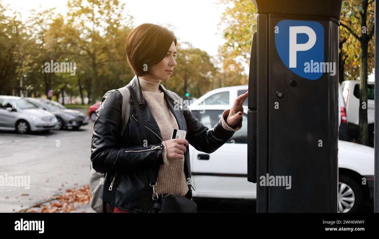 La donna paga il parcheggio tramite parchimetro utilizzando carta di credito Foto Stock