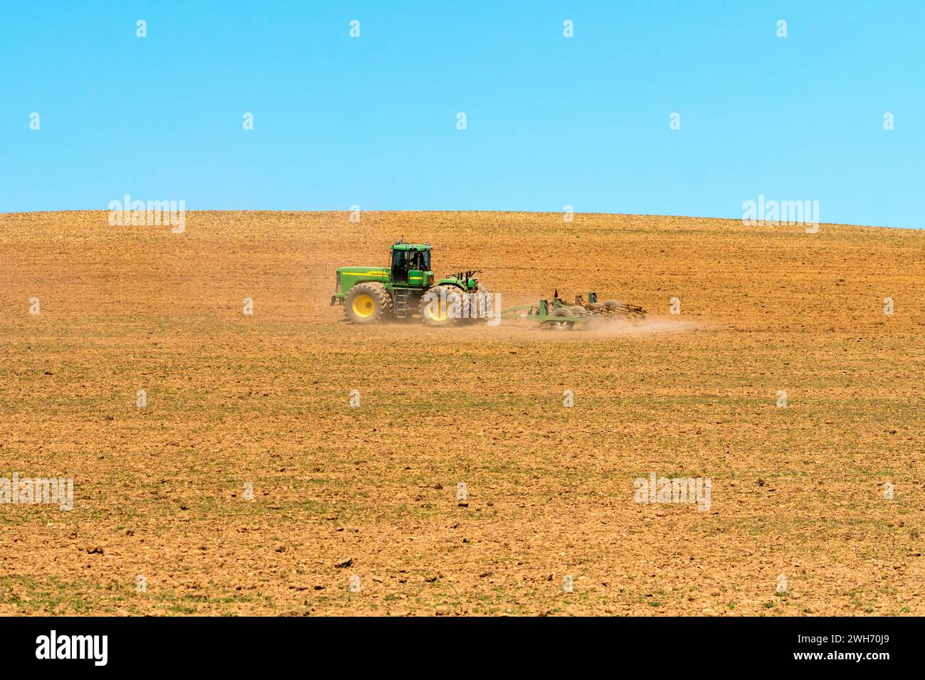 Paesaggio agricolo di un trattore John Deere primo piano durante l'aratura primaverile a Overberg, Capo Occidentale, Sud Africa Foto Stock