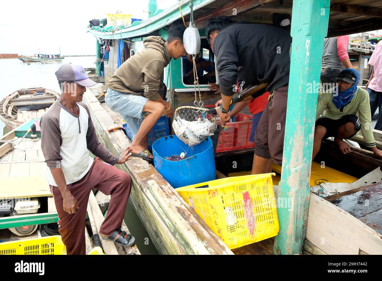 Lampung, Indonesia, 7 ottobre 2022: Gli uomini indonesiani selezionano il pesce in un cesto su un peschereccio a Lampung, Indonesia. Foto Stock