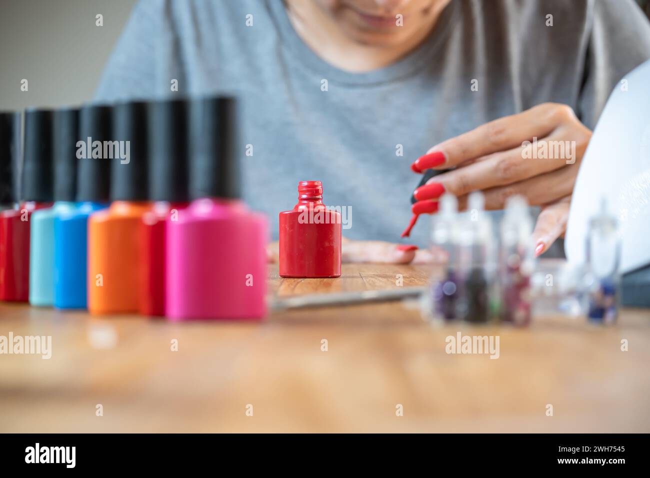 Donna che dipinge le unghie a casa, usando un colore rosso brillante. Foto Stock