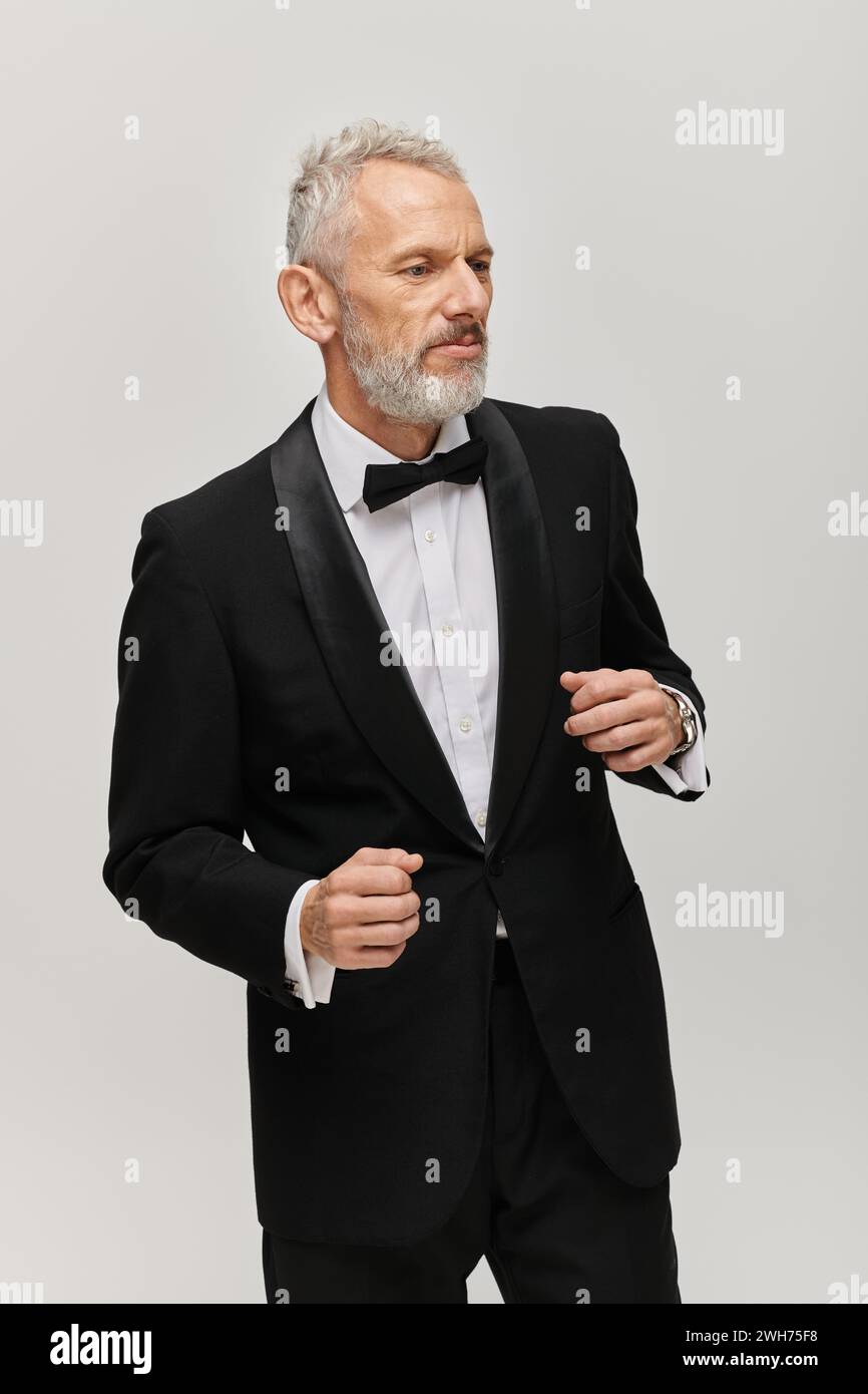 attraente uomo maturo con barba in smoking nero con fiocco che posa in movimento mentre balla Foto Stock