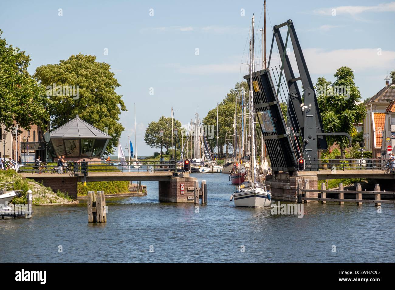 Barca a vela che passa ponte levatoio aperto da est a ovest del porto nella città di Medemblik, Noord-Holland, Paesi Bassi Foto Stock