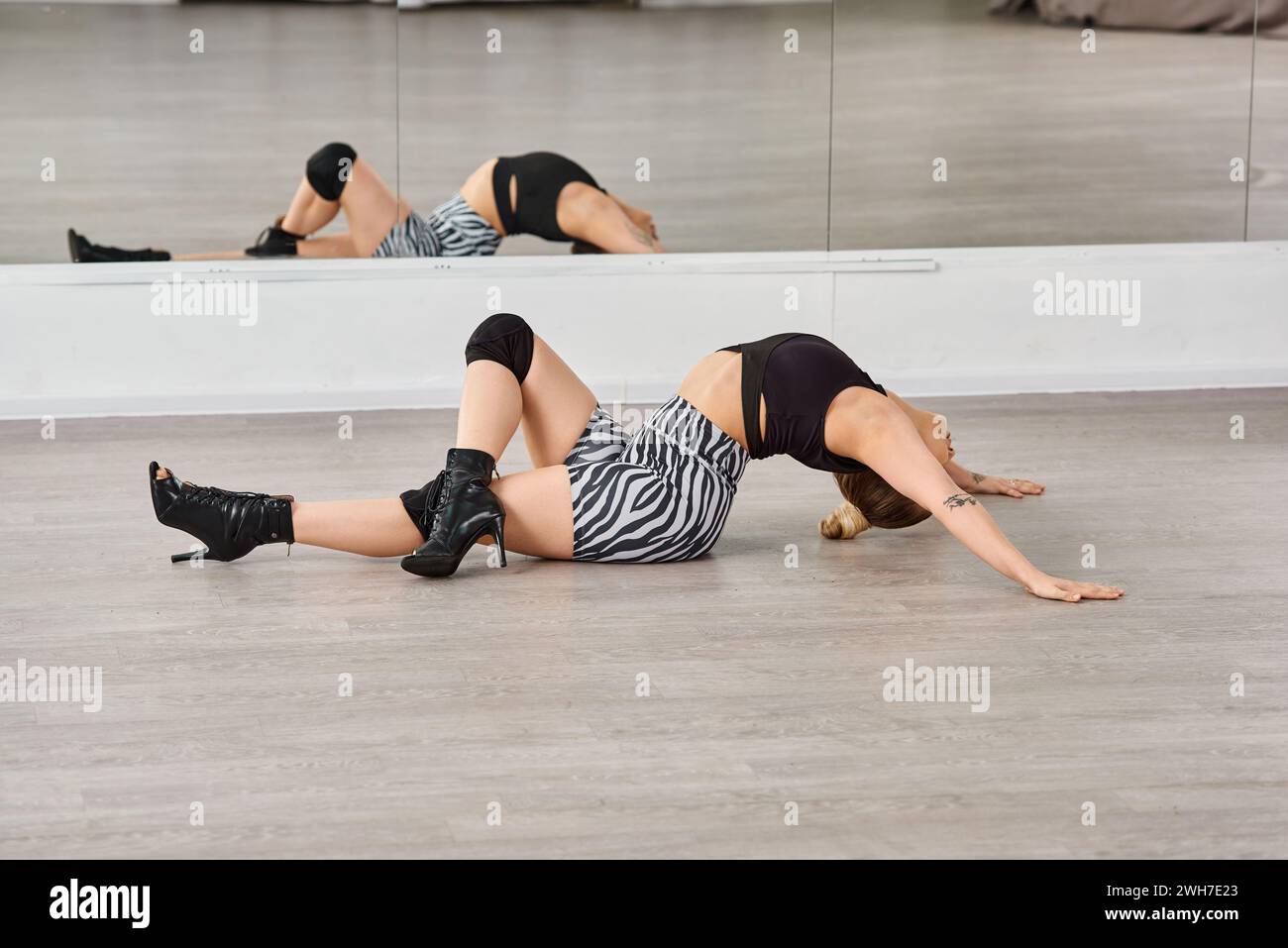 Una donna aggraziata giace sul pavimento mentre si esibisce a ballare, con il ginocchio e la caviglia che sostengono il suo corpo Foto Stock