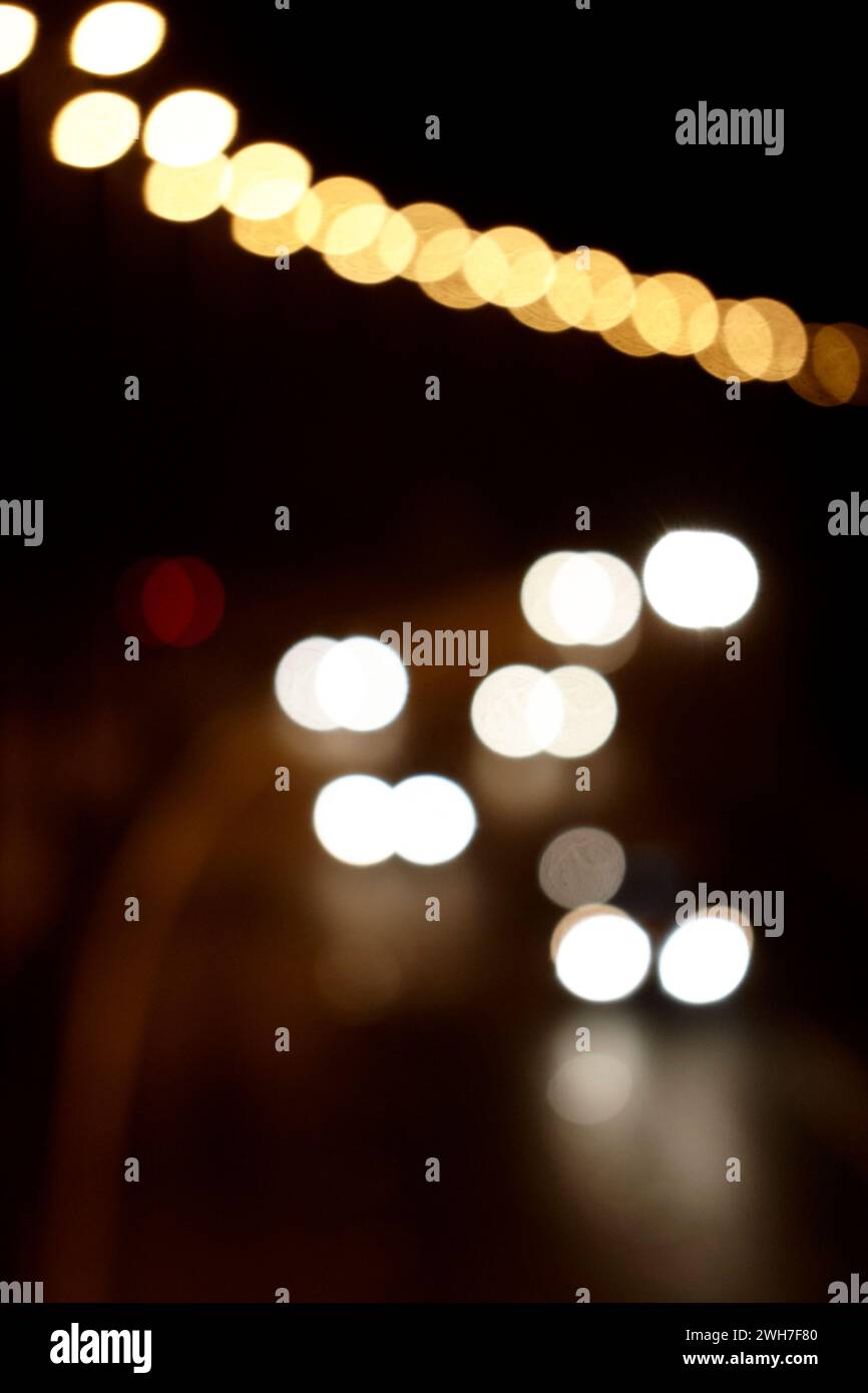 fari di auto che guidano lungo un'autostrada illuminata di notte, immagine concettuale sfocata e sfocata Foto Stock