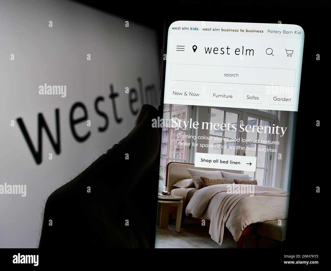 Persona con smartphone con pagina web della società West Elm di fronte al logo aziendale. Messa a fuoco al centro del display del telefono. Foto Stock