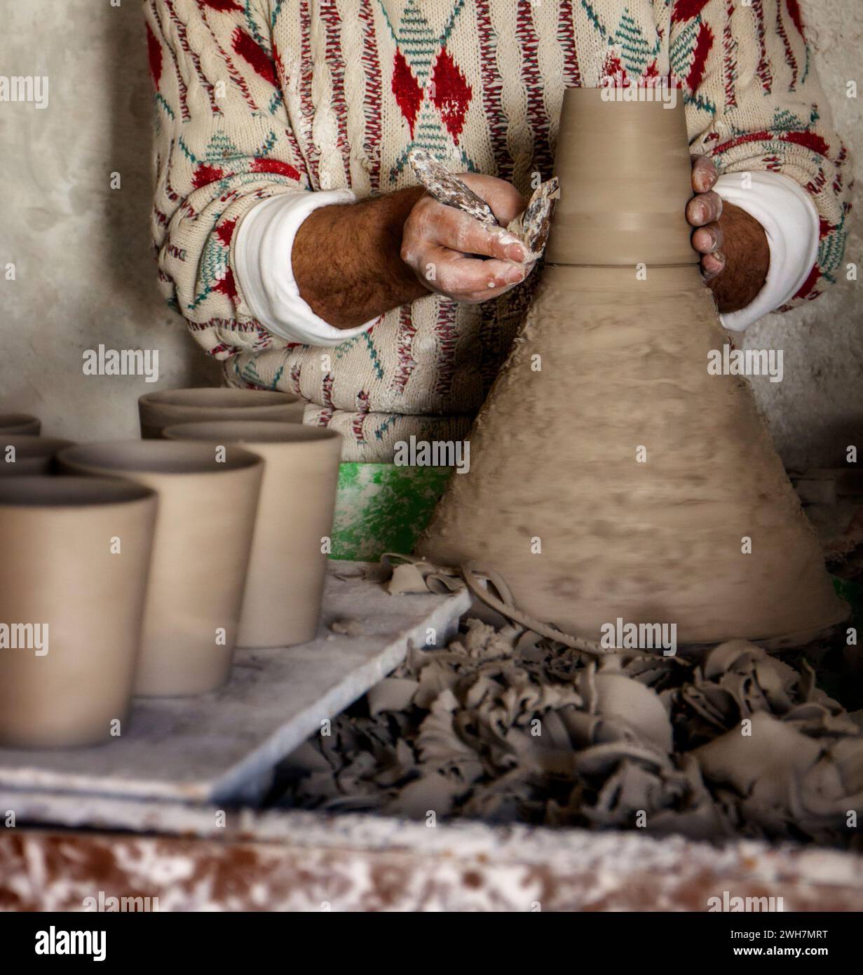 vasaio marocchino che lancia a mano un gruppo di tazze di argilla su una ruota per la vendita sul mercato Foto Stock