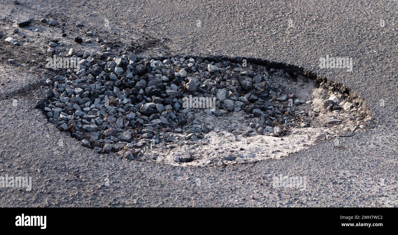 Grande fossa sulla strada. Concetto di riparazione della pavimentazione e sostituzione dell'asfalto. Foto Stock