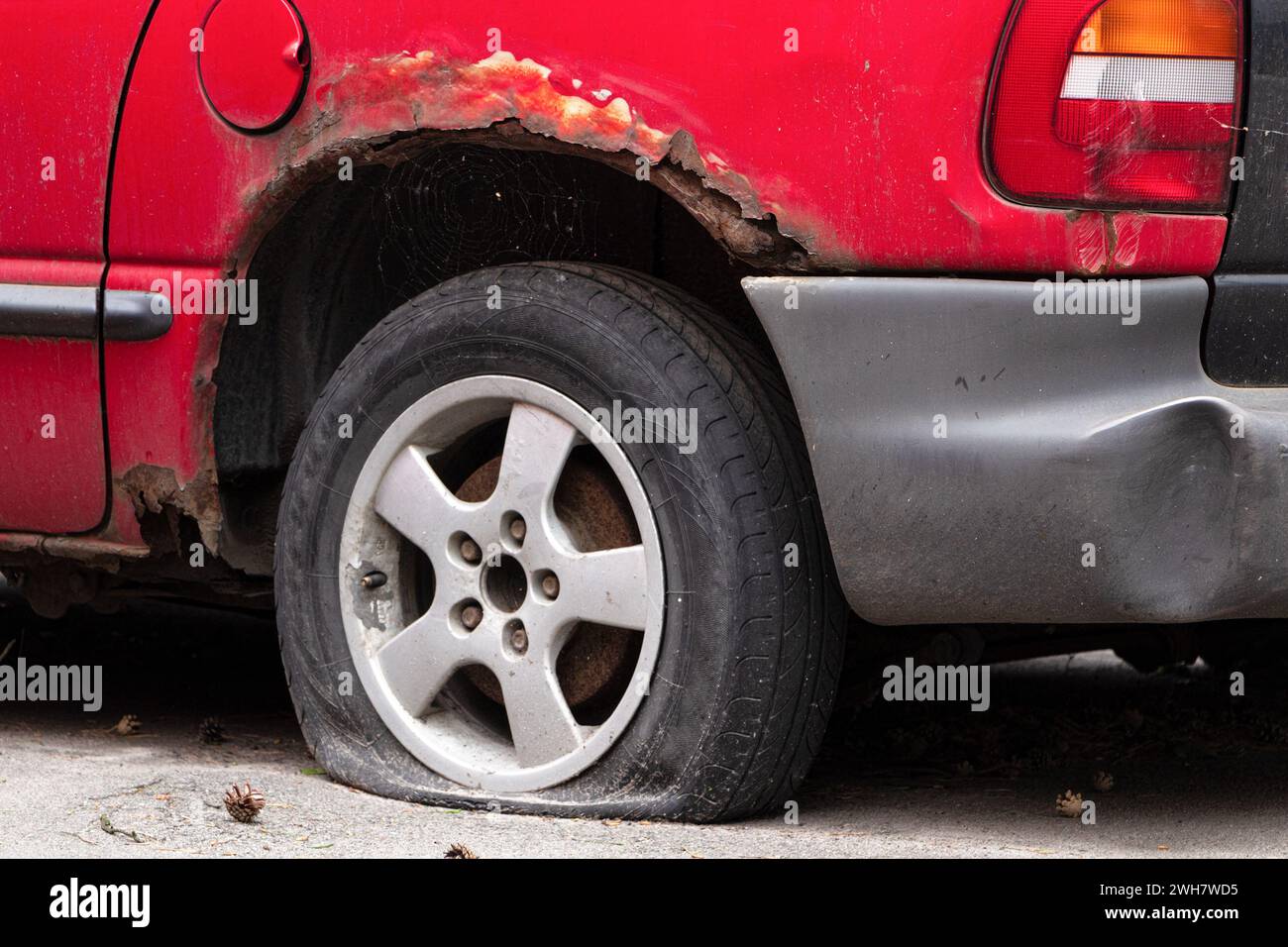 Il retro di una vecchia auto arrugginita con una ruota perforata. Riciclare vecchie auto. Foto Stock