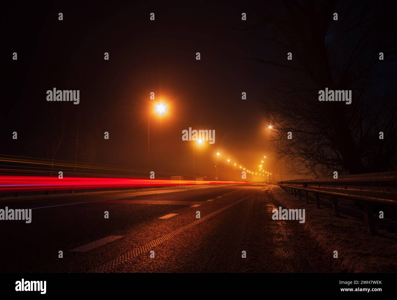 Autostrada vuota con sentieri leggeri che partono dall'auto di passaggio di notte. Foto Stock