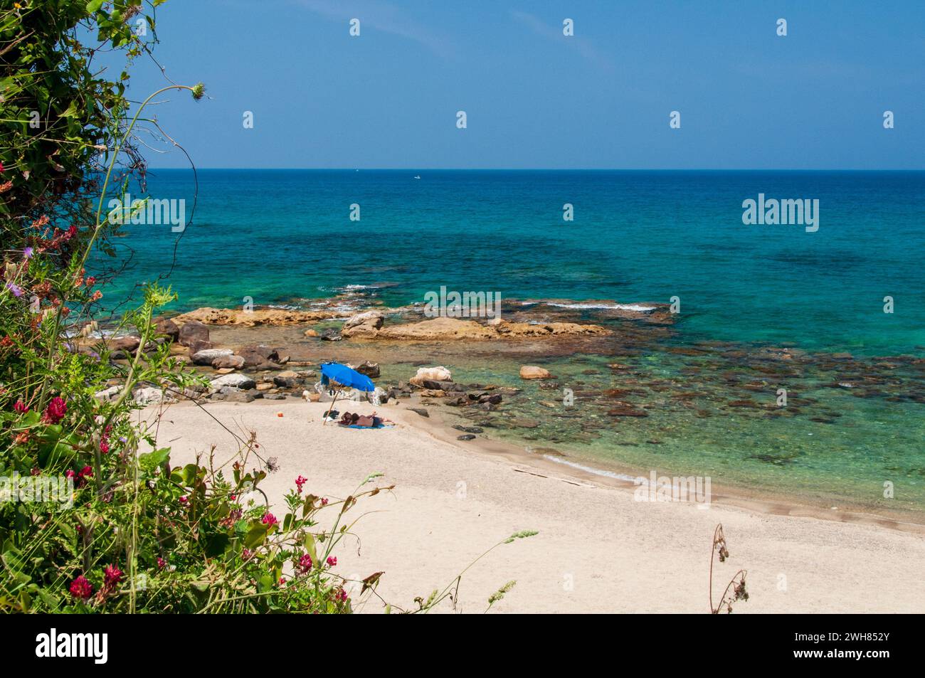 Strandsituation ein paar unter einem blauen Sonnenschirm in der Nähe von Pizzo auf Sizilien Foto Stock