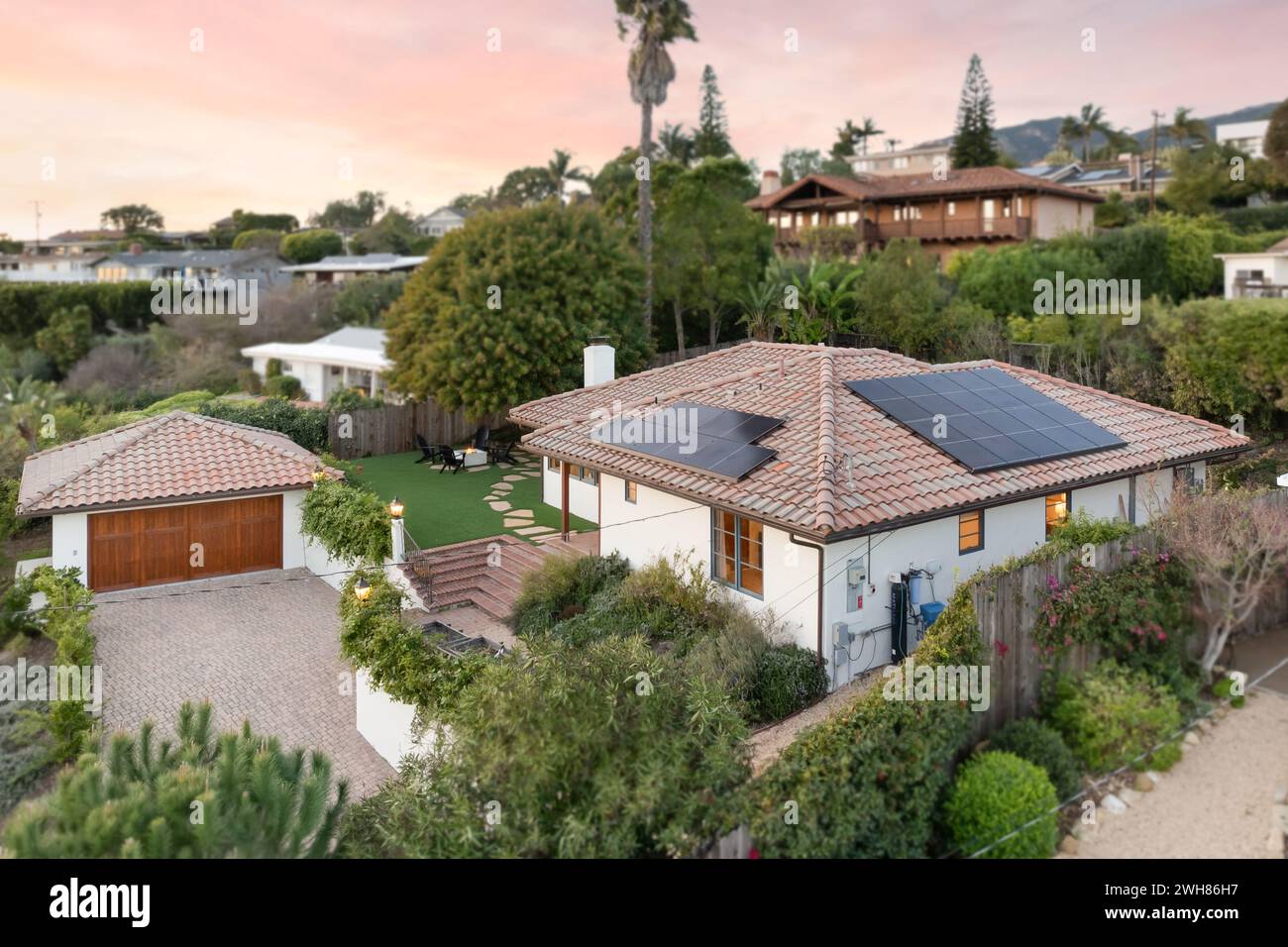 Una casa moderna con un cortile rialzato e tetto coperto da pannelli solari Foto Stock
