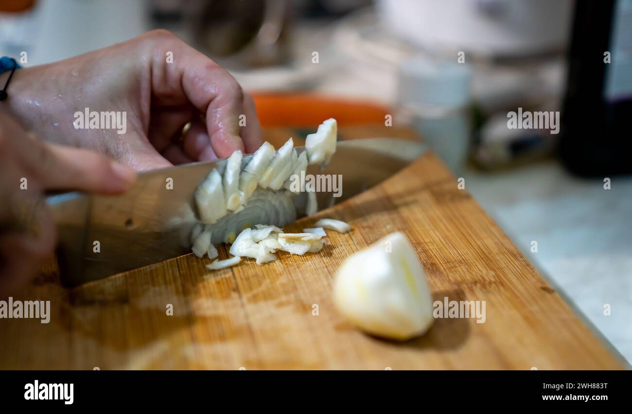 Una persona affetta l'aglio utilizzando un coltello su un piano portapaziente Foto Stock