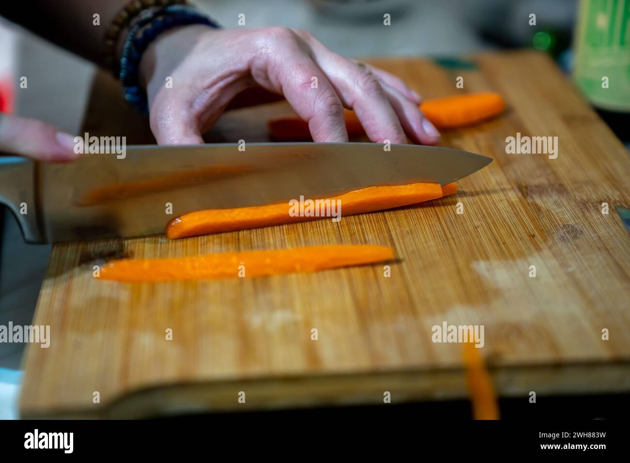 Una persona che affetta sapientemente le carote con un coltello su un tagliere Foto Stock