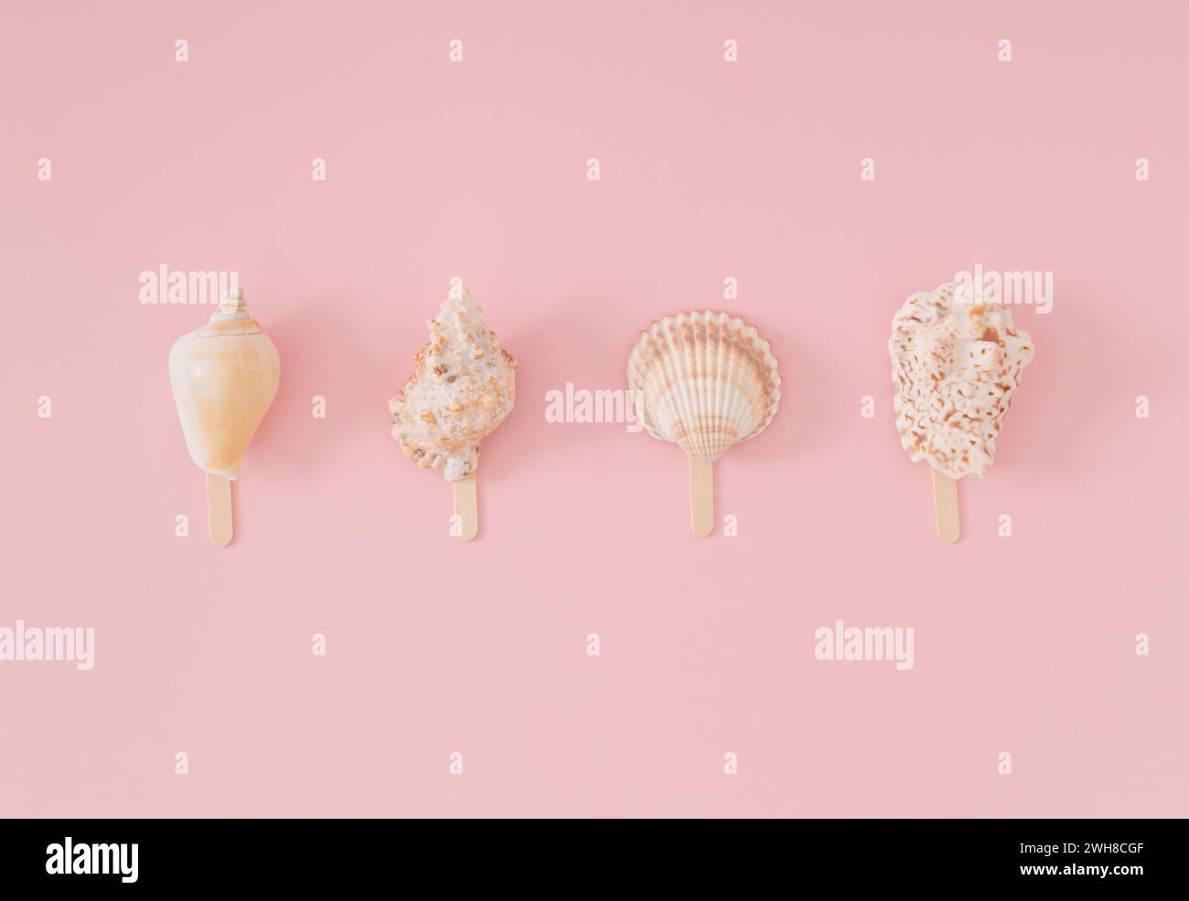 Layout estivo alla moda di conchiglie di mare con bacchette di gelato su sfondo rosa chiaro e piccante. Concetto estivo minimalista. Un'idea creativa per il cibo da spiaggia. Gelato A. Foto Stock