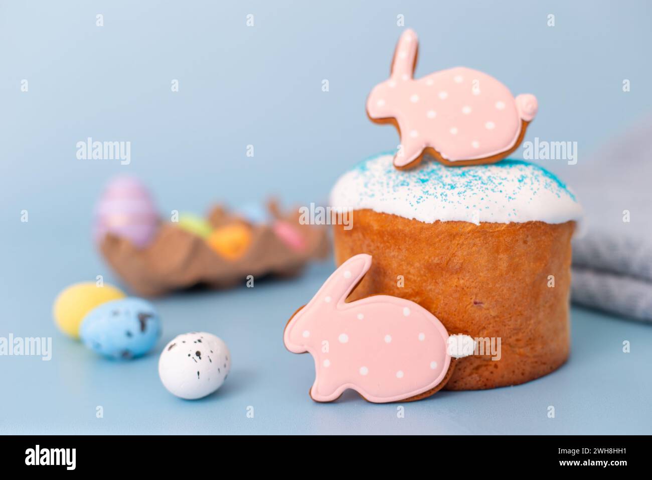 Pan di zenzero rosa sotto forma di coniglio su una torta pasquale su sfondo blu Foto Stock