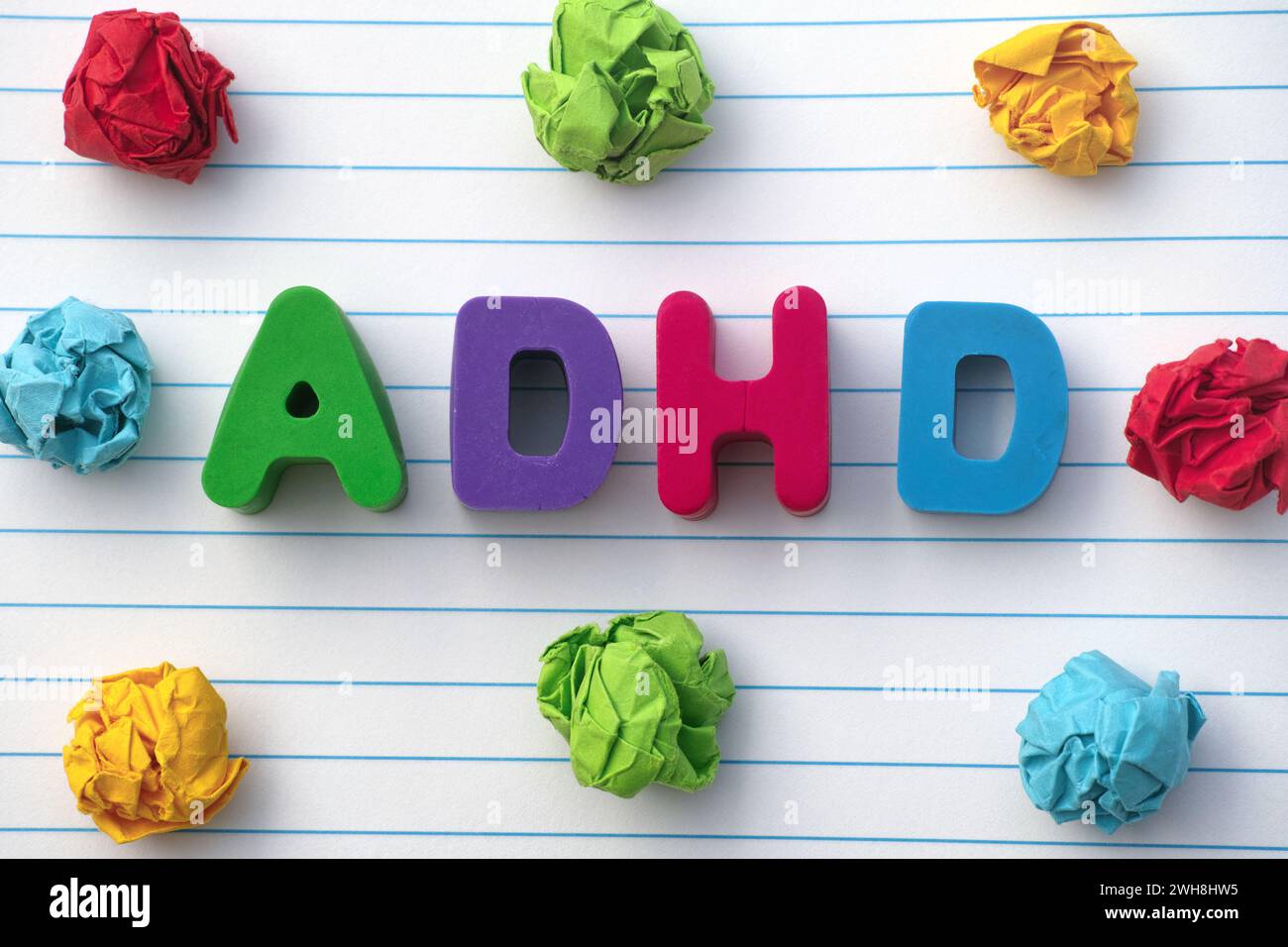 ADHD. L'abbreviazione ADHD su un foglio di notebook con delle palline di carta colorate e increspate intorno. Primo piano. ADHD è l'acronimo di Attention deficit hyperac Foto Stock