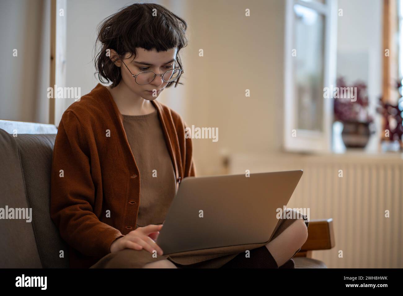 Adolescente concentrata che lavora, studia a casa in condizioni confortevoli utilizzando un computer portatile Foto Stock