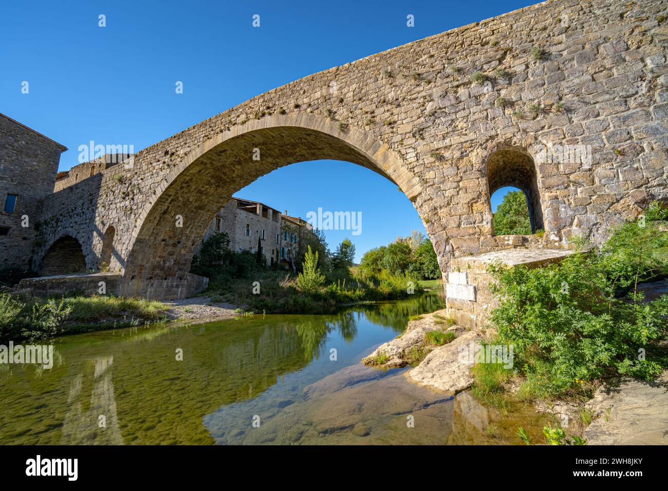 Il vecchio ponte medievale in pietra di Lagrasse, in Francia, è stato portato in una soleggiata mattinata di primavera senza gente. Foto Stock