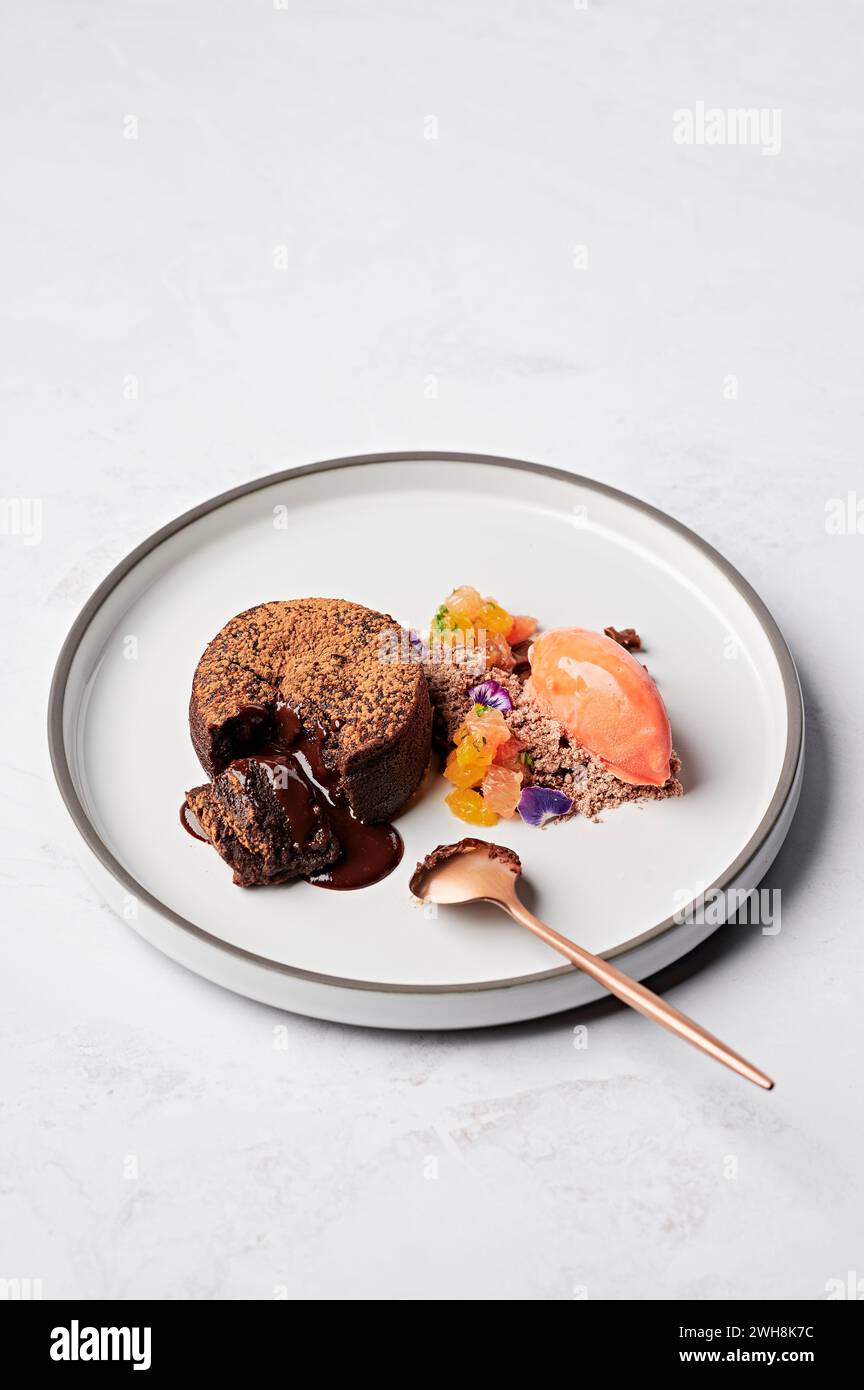 Fondente al cioccolato caldo, frammenti di agrumi Cointreau, neve gianduja, sorbetto all'arancia rossa Foto Stock