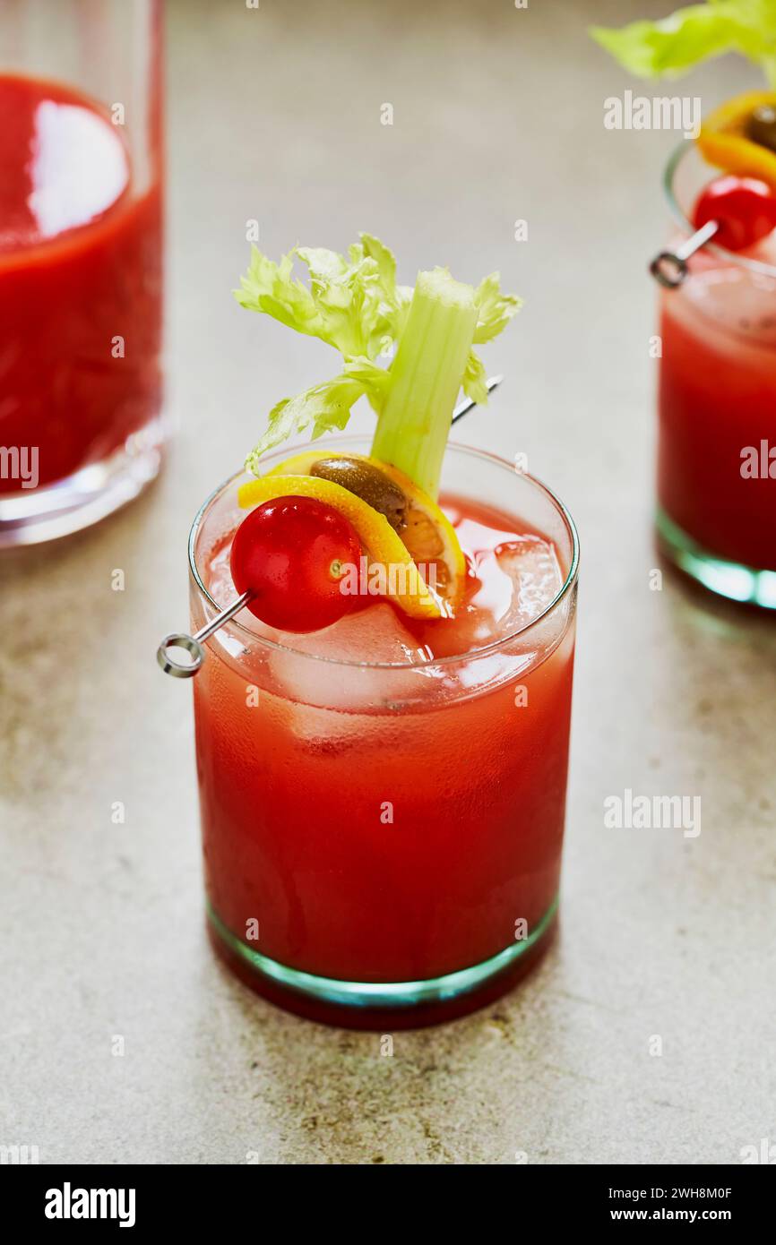 Bloody Mary cocktail con sedano, pomodoro e Olive Garnish su una superficie verde salvia Foto Stock