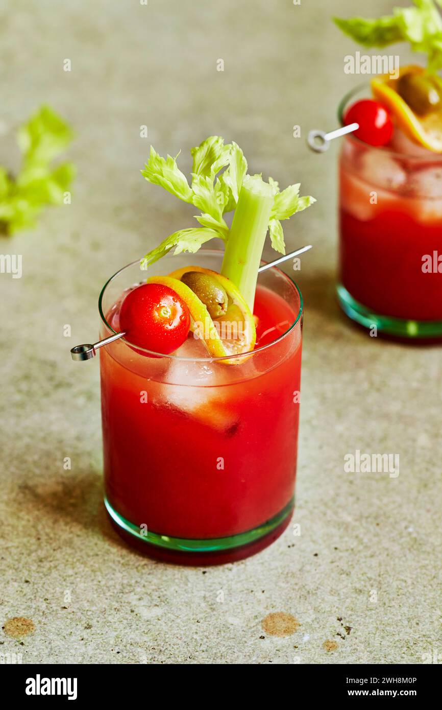 Bloody Mary cocktail con sedano, pomodoro e Olive Garnish su una superficie verde salvia Foto Stock