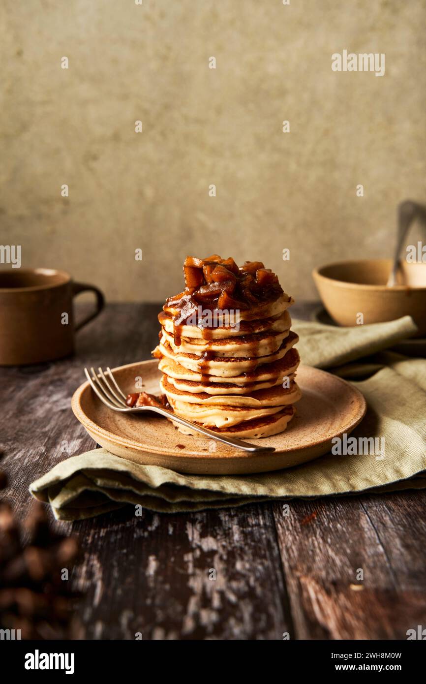 Pila di pancake alla cannella di mele su superficie in legno e sfondo verde salvia Foto Stock