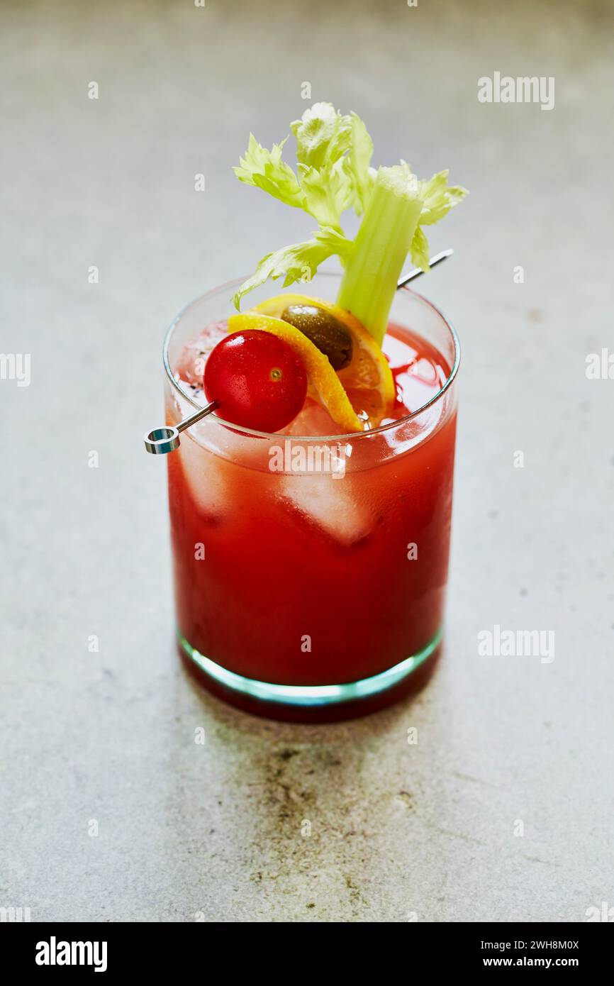 Bloody Mary cocktail con sedano, pomodoro e Olive Garnish su una superficie verde salvia Foto Stock