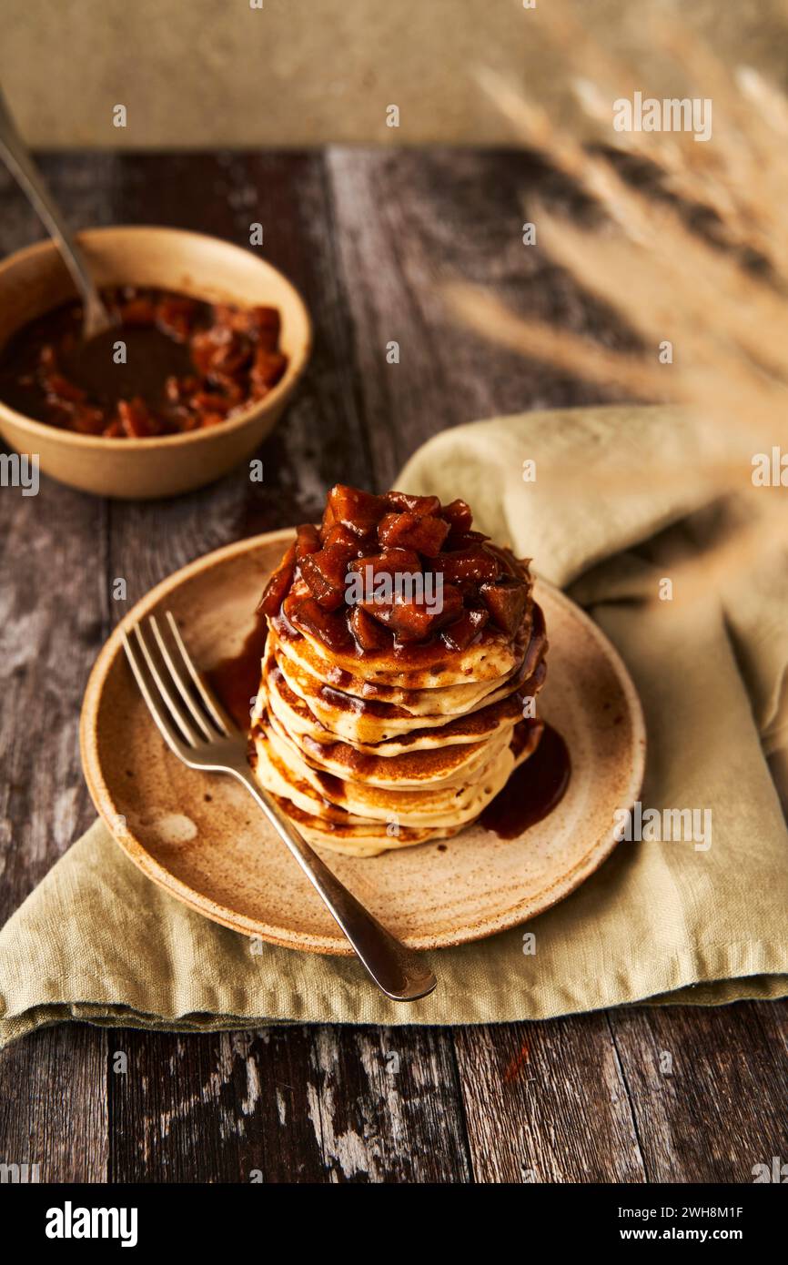 Pila di pancake alla cannella di mele su superficie in legno e sfondo verde salvia Foto Stock