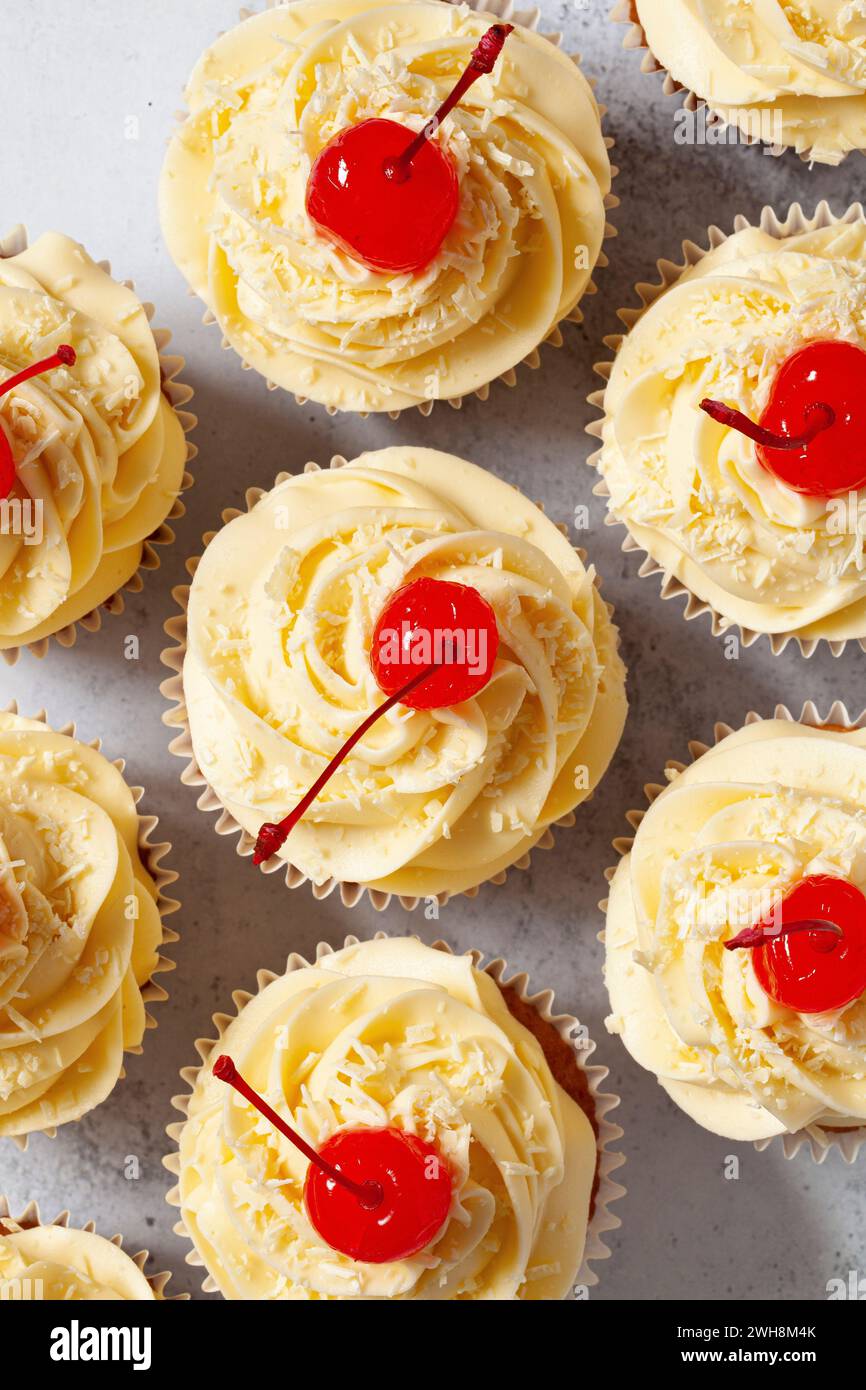 Vista dall'alto dei cupcake ricoperti di crema di burro, scaglie di cioccolato bianco e ciliegie al Maraschino Foto Stock